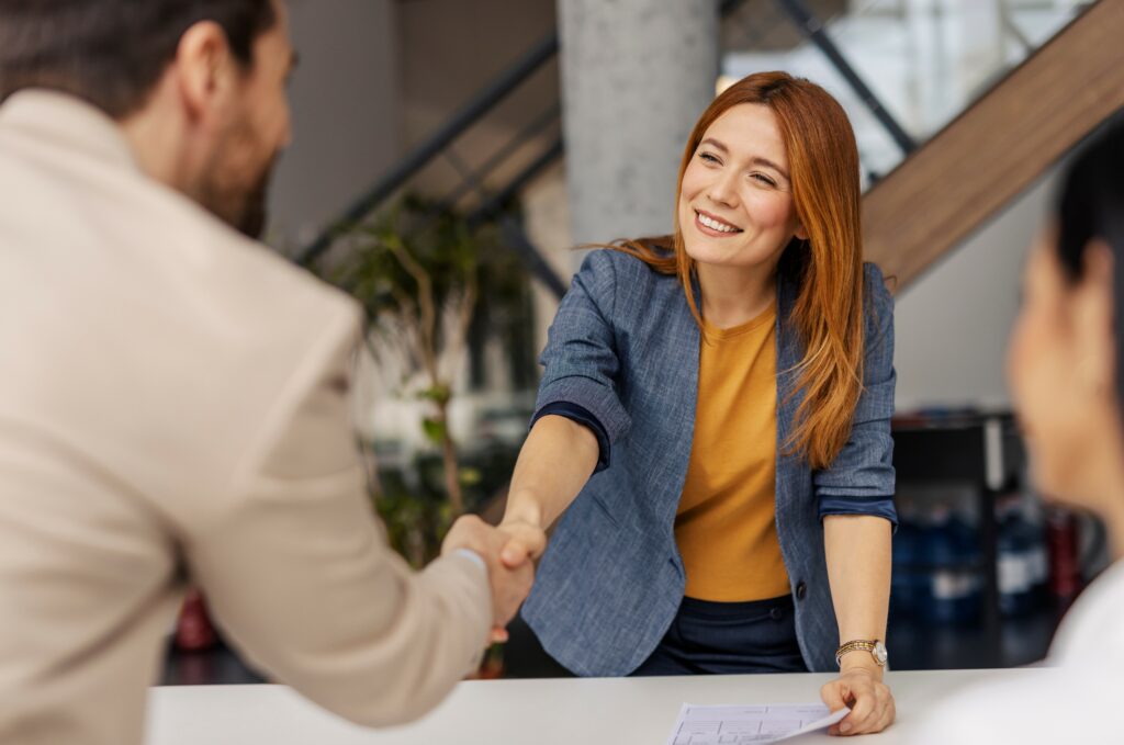 Portrait of friendly female boss shaking hands with new team member on sprint meeting.