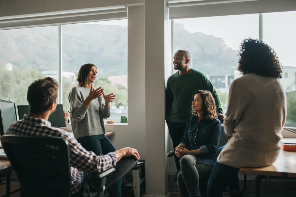 Diverse group of designers discussing a project together during a meeting around their desks in their startup office